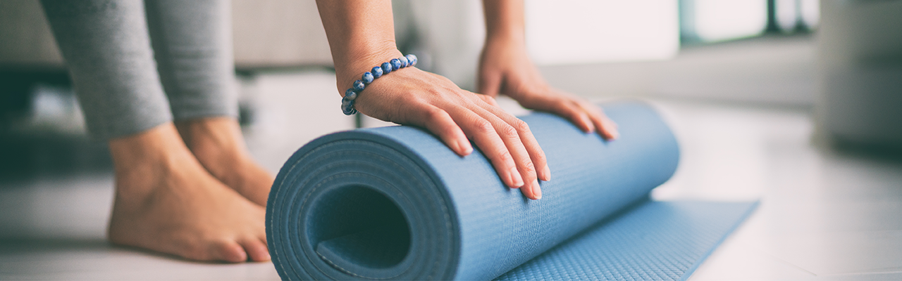 Foto einer Frau, die eine Yoga-Matte ausrollt